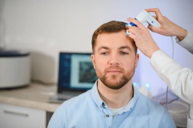 Bir tricholog, saç dökülmesine başlayan bir adamın saçını inceliyor. Bir dermatologla görüşeceğim. Saç dökülmesi, alopezi, pruritus, yanmakta olan kafa ya da sebora.