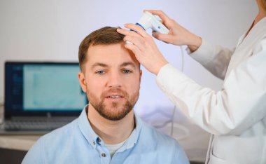 Bir tricholog, saç dökülmesine başlayan bir adamın saçını inceliyor. Bir dermatologla görüşeceğim. Saç dökülmesi, alopezi, pruritus, yanmakta olan kafa ya da sebora.