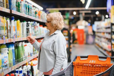 Kadın süpermarketten ev kimyasalları ya da çamaşır deterjanı alıyor..