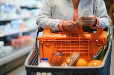 Yaşlı bir kadının ellerinde bir süpermarkette bakkaliye fişi var. Yüksek fiyatlar kavramı.