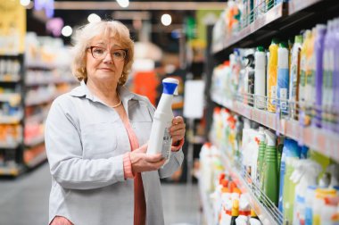 Kadın süpermarketten ev kimyasalları ya da çamaşır deterjanı alıyor..