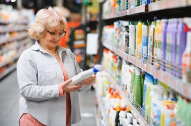 Evdeki kimyasallardan alışveriş yapan, şişelerdeki etiketleri okuyan ilginç bir kadın..