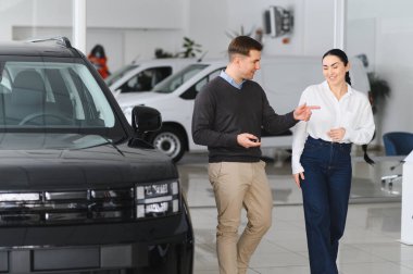 Mutlu genç çift aile için yeni bir araba seçer ve alır. Galeriyi ziyaret ediyorum..