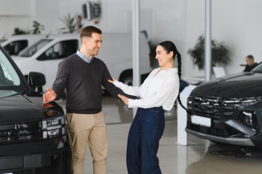 Galeriye başarılı bir ziyaret. Mutlu genç çift aile için yeni bir araba seçer ve alır..