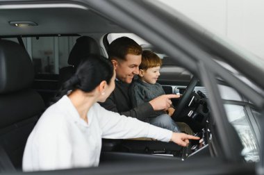 Araba galerisinde bir aile. Mutlu bir aile galeride bir araba satıcısıyla anlaşma yapmış. Mutlu aile galeride yeni bir araba seçiyor.