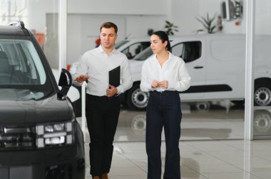 Güzel genç kadın yakışıklı araba Bayilik işçi için bir araba içinde Bayilik seçerken konuşuyor.