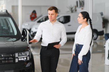 Güzel genç kadın yakışıklı araba Bayilik işçi için bir araba içinde Bayilik seçerken konuşuyor.