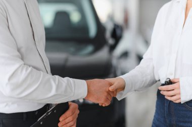 Satıcı ve müşteri bir araba galerisinde el sıkışıyor..