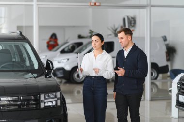 Sakallı bir erkek alıcı araba galerisinden bir araba satıcısının yardımıyla araba seçer. Satın alma, kiralama ve araba servisi kavramı.