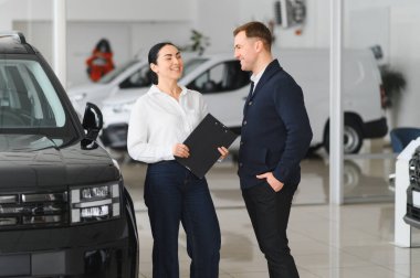 Sakallı bir erkek alıcı araba galerisinden bir araba satıcısının yardımıyla araba seçer. Satın alma, kiralama ve araba servisi kavramı.