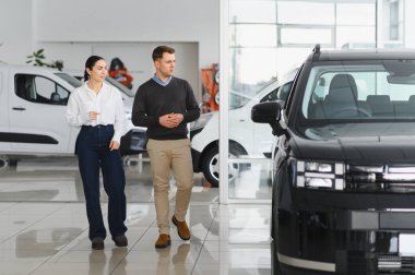 Galeriye başarılı bir ziyaret. Mutlu genç çift aile için yeni bir araba seçer ve alır..