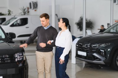 Galeriye başarılı bir ziyaret. Mutlu genç çift aile için yeni bir araba seçer ve alır..