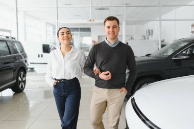 Galeriye başarılı bir ziyaret. Mutlu genç çift aile için yeni bir araba seçer ve alır..