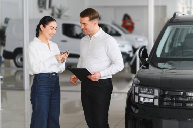 Güzel genç kadın yakışıklı araba Bayilik işçi için bir araba içinde Bayilik seçerken konuşuyor.