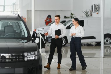 Güzel genç kadın yakışıklı araba Bayilik işçi için bir araba içinde Bayilik seçerken konuşuyor.