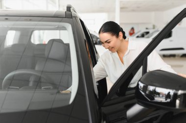 Güzel genç bayan yeni arabasına zevkle dokunuyor..