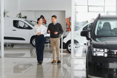 Otomobil galerisinde yeni lüks arabaları kontrol eden çift..