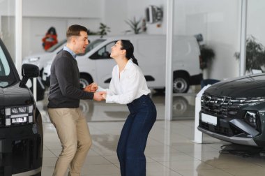 Otomobil galerisinde yeni lüks arabaları kontrol eden çift..