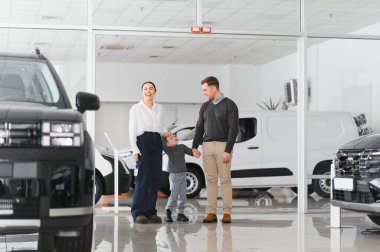 Araba galerisinde bir aile. Mutlu bir aile galeride bir araba satıcısıyla anlaşma yapmış. Mutlu aile galeride yeni bir araba seçiyor.