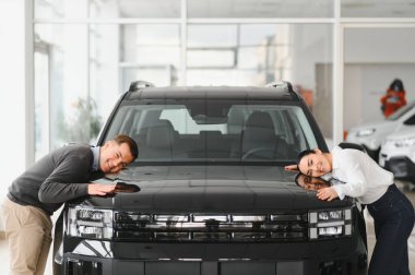 Otomobil galerisinde yeni lüks arabaları kontrol eden çift..