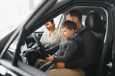 Araba galerisinde bir aile. Mutlu bir aile galeride bir araba satıcısıyla anlaşma yapmış. Mutlu aile galeride yeni bir araba seçiyor.