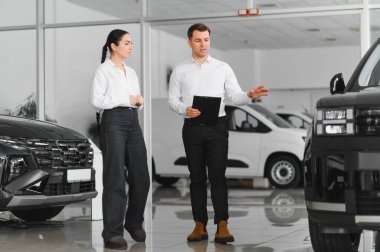 Güzel genç kadın yakışıklı araba Bayilik işçi için bir araba içinde Bayilik seçerken konuşuyor.