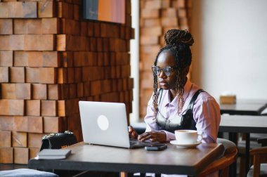 Kafedeki tezgahta tek başına oturan odaklanmış genç Afrikalı kadın..