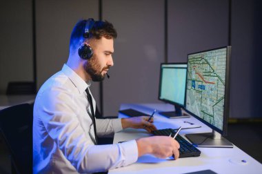 Tamirat merkezi. Seyrüsefer kontrol panosunda otururken mikrofonla çalışan bir adamın portresi.