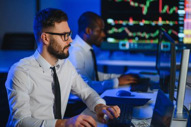 Finansal Analizci İş Gecesinde Yatırım Bankeriyle Konuşuyor. Çoklu Monitör Çalışma İstasyonunda Gerçek Zaman Stok Çizelgesi Verisi Hakkında Sohbet