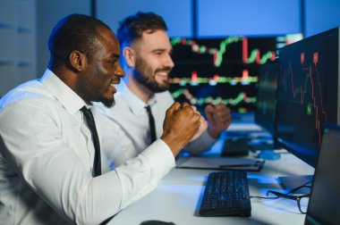 Finansal Analizci İş Gecesinde Yatırım Bankeriyle Konuşuyor. Çoklu Monitör Çalışma İstasyonunda Gerçek Zaman Stok Çizelgesi Verisi Hakkında Sohbet