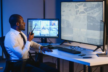 Afro-Amerikalı güvenlik görevlisi kontrol odasında telsizle konuşuyor..