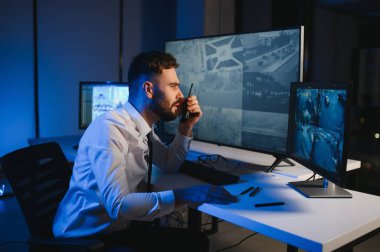 Güvenlik kamerası görüntülerini ve haritayı bilgisayarda izleyen bir adam..