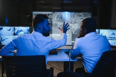 Güvenlik Kontrol Odası İki Subay Şüpheli Faaliyetler İçin Çoklu Ekranları İzlerken Telsiz ile İzinsiz Faaliyetler Raporluyorlar. Ulusal Önemliliğin İtirazını Korurlar.