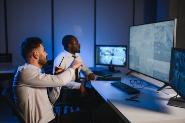 Güvenlik Kontrol Odası İki Subay Şüpheli Faaliyetler İçin Çoklu Ekranları İzlerken Telsiz ile İzinsiz Faaliyetler Raporluyorlar. Ulusal Önemliliğin İtirazını Korurlar.