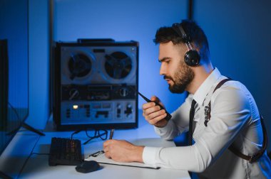 Gizli ajan kayıt cihazını dinliyormuş. Memur kulaklıkla dinleme yapıyor..