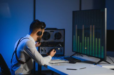 Gizli ajan kayıt cihazını dinliyormuş. Memur kulaklıkla dinleme yapıyor..