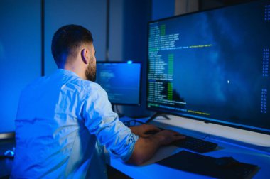 Geceleri ofiste erkek programcının portresi.