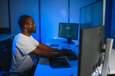 Bilgisayarda çalışan bilişim programcısı. Erkek Uzman Yaratıcı Yenilikçi Yazılım Mühendisliği Geliştirme Uygulaması, Program, Video Oyunu. Kodlama Dili Terminali. Omuz üstünden.