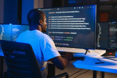 Bilgisayarda çalışan bilişim programcısı. Erkek Uzman Yaratıcı Yenilikçi Yazılım Mühendisliği Geliştirme Uygulaması, Program, Video Oyunu. Kodlama Dili Terminali. Omuz üstünden.