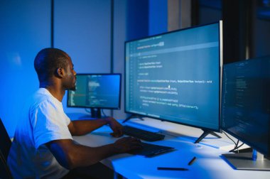 Bilgisayarda çalışan bilişim programcısı. Erkek Uzman Yaratıcı Yenilikçi Yazılım Mühendisliği Geliştirme Uygulaması, Program, Video Oyunu. Kodlama Dili Terminali. Omuz üstünden.