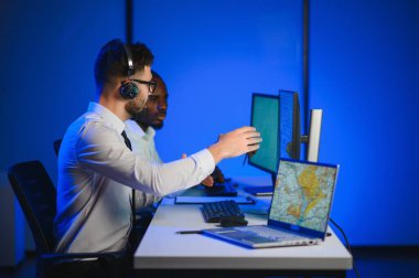 Tamirat merkezi. Seyrüsefer kontrol panosunda otururken mikrofonla çalışan erkeklerin portresi.