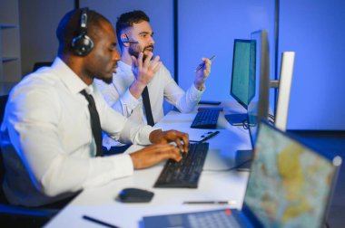 Erkek Veri Bilimadamı, Büyük Altyapı Kontrol ve İzleme Odası 'nda Kulaklık Takan Kişisel Bilgisayarda Çalışıyor. İş Çağrı Merkezi Ofisi 'nde Genç Mühendis