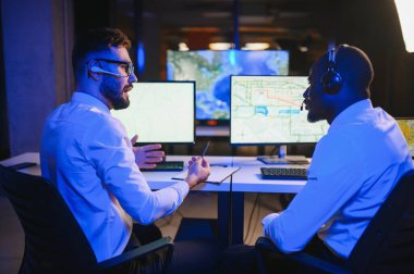 Tamirat merkezi. Seyrüsefer kontrol panosunda otururken mikrofonla çalışan erkeklerin portresi.