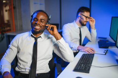 Erkek Veri Bilimadamı, Büyük Altyapı Kontrol ve İzleme Odası 'nda Kulaklık Takan Kişisel Bilgisayarda Çalışıyor. İş Çağrı Merkezi Ofisi 'nde Genç Mühendis