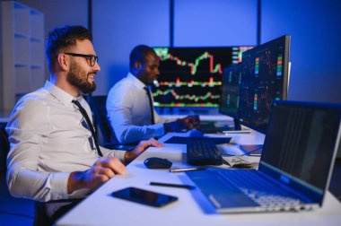 Finansal Analizci İş Gecesinde Yatırım Bankeriyle Konuşuyor. Çoklu Monitör Çalışma İstasyonunda Gerçek Zaman Stok Çizelgesi Verisi Hakkında Sohbet