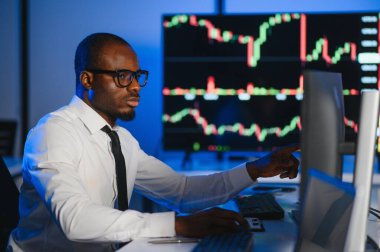 Gerçek zamanlı hisse senetleri, emtialar ve borsa grafikleri ile birlikte Multi-Monitor Workstation ile bilgisayar üzerinde çalışan finansal analist. Afrikalı Amerikalı İşadamı Gece Yatırım Bankası 'nda çalışıyor.