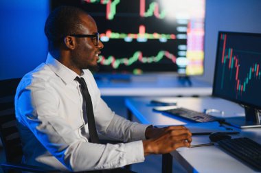 Gerçek zamanlı hisse senetleri, emtialar ve borsa grafikleri ile birlikte Multi-Monitor Workstation ile bilgisayar üzerinde çalışan finansal analist. Afrikalı Amerikalı İşadamı Gece Yatırım Bankası 'nda çalışıyor.