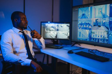 Afro-Amerikalı güvenlik görevlisi kontrol odasında telsizle konuşuyor..