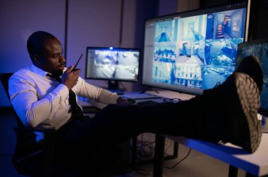 Afro-Amerikalı güvenlik görevlisi kontrol odasında telsizle konuşuyor..