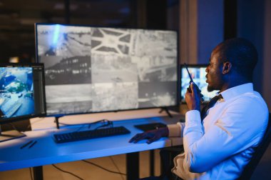 Afro-Amerikalı güvenlik görevlisi kontrol odasında telsizle konuşuyor..